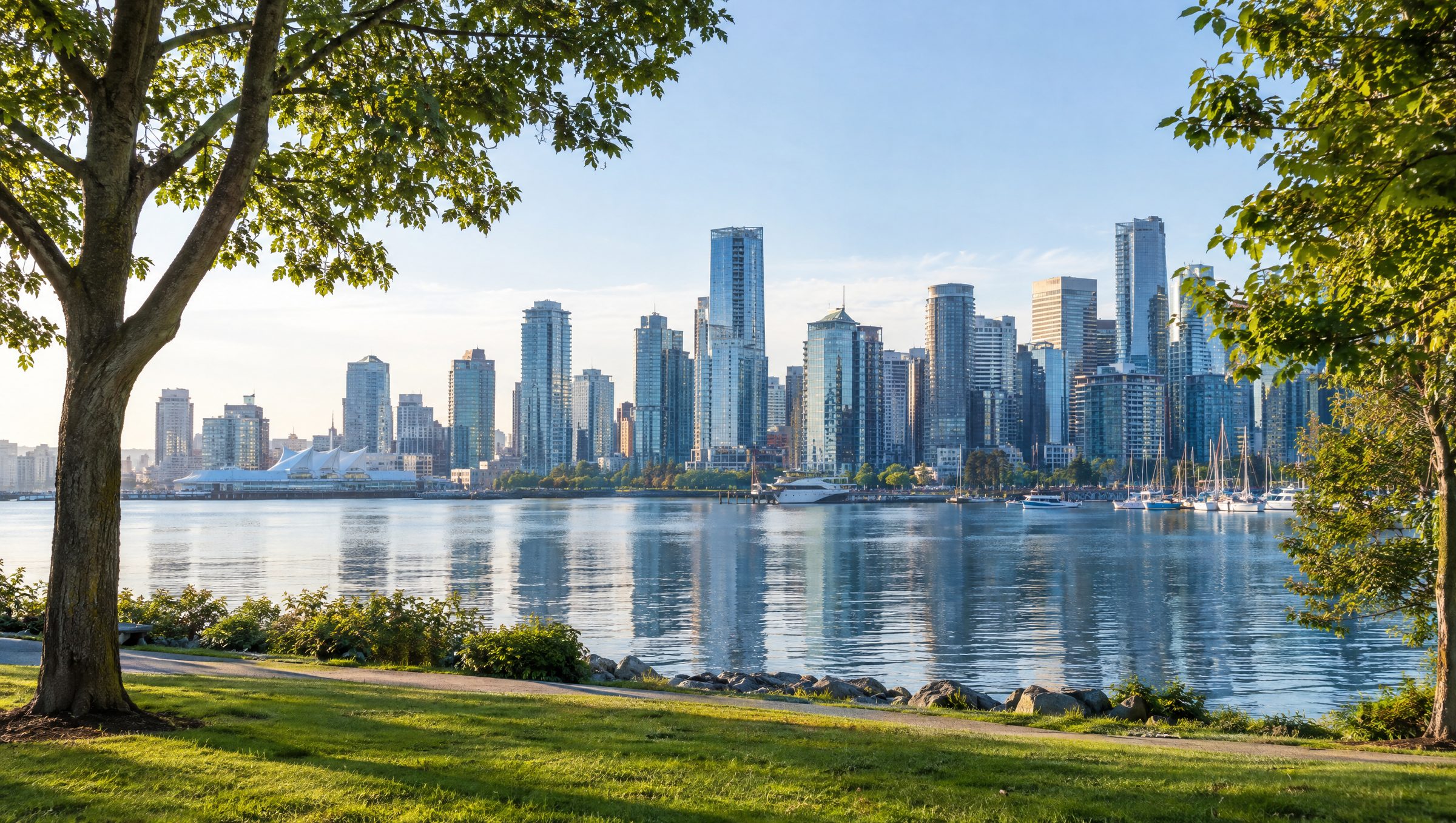A city skyline across a calm harbour, seen from a waterfront park in the morning